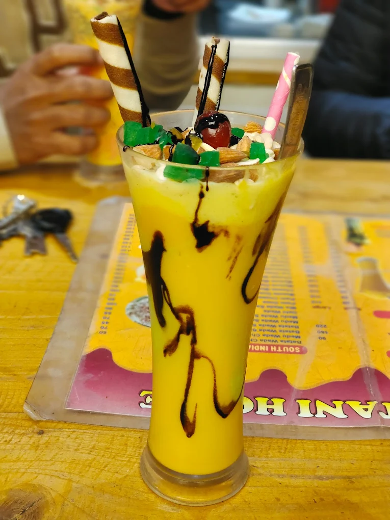 Retro café interior blurred behind a bright yellow mango mastani in foreground