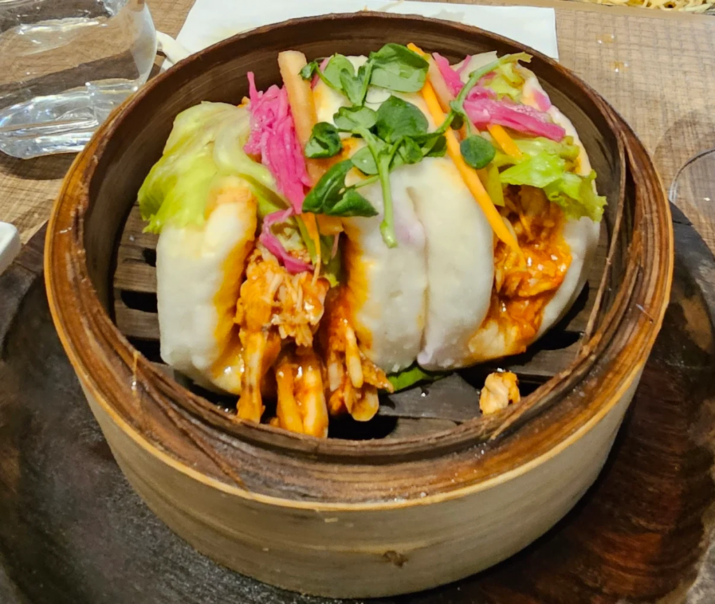 Dim sum in bamboo steamer with chopsticks, on-image text ‘Pan-Asian Delights Pune’, puneripages.in