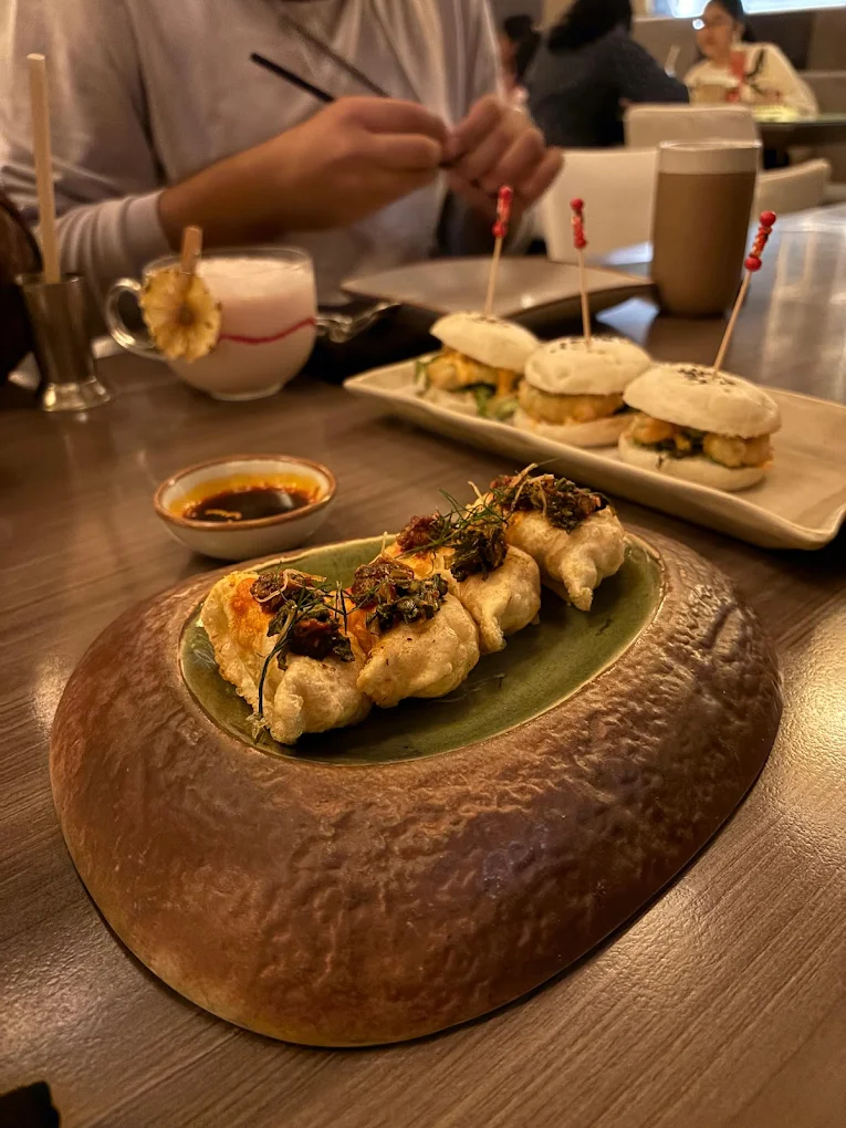 Dim sum in bamboo steamer with chopsticks, on-image text ‘Pan-Asian Delights Pune’, puneripages.in