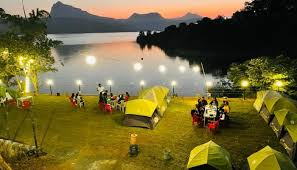 Camp tents pitched along Pawna Lake’s calm waters with adjacent hill forts at dusk.