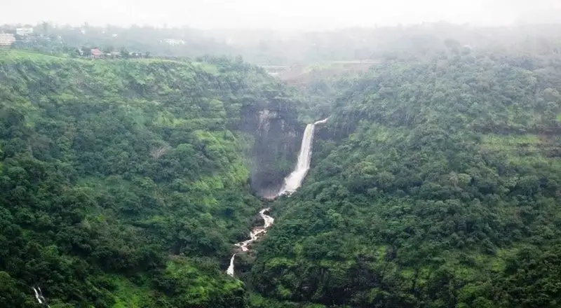 Three-tiered Kune Waterfalls plummeting down Sahyadri slopes surrounded by vibrant greenery.