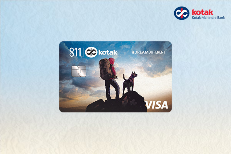Close-up of Kotak 811 #DreamDifferent credit card showing a hiker and dog silhouette on a blue gradient background, with Visa logo and contactless symbol.