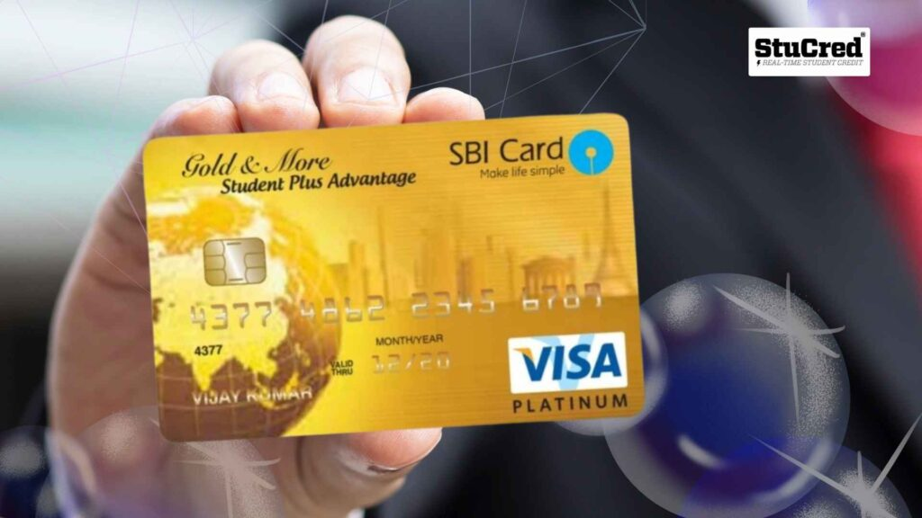 Hand holding a golden SBI Student Plus Advantage credit card featuring a globe motif and Visa Platinum logo against a blurred background.