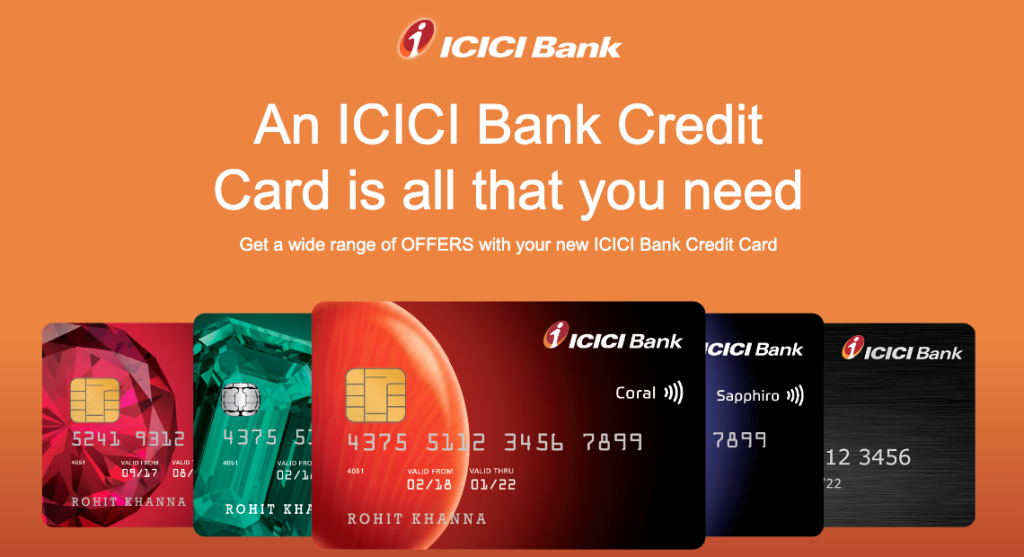 ICICI Bank Coral RuPay credit card in coral-red held between two fingers, displaying the contactless payment icon and embedded chip.