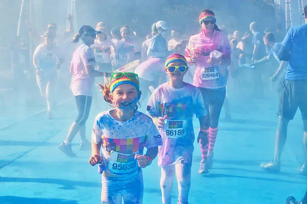 Participants of the Pune Color Run doused in colored powder as they jog past cheering volunteers.