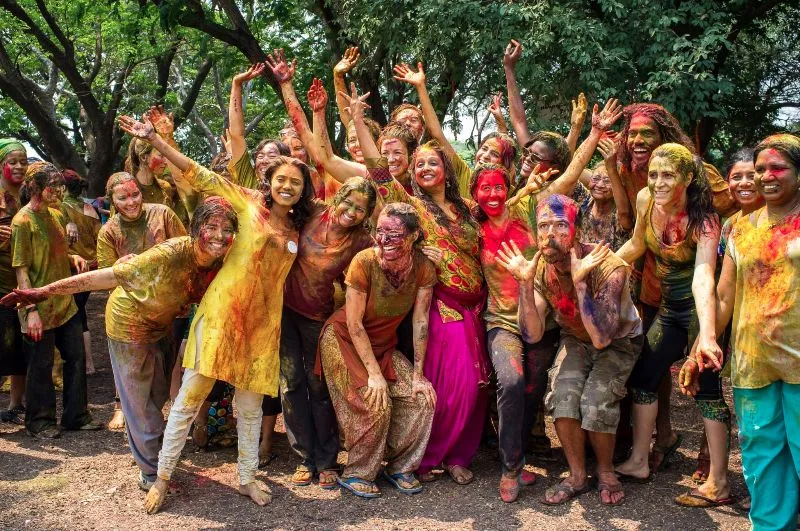 Visitors tossing Holi colors near food trucks and artisan stalls at the Kalyani Nagar color carnival.