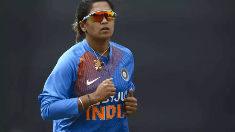 Veda Krishnamurthy walking off cricket field during sunset, bat raised, farewell moment