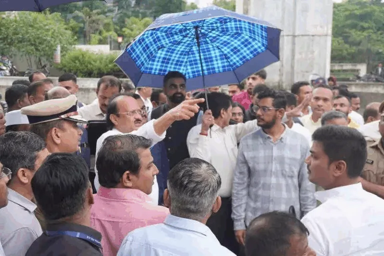 Ajit Pawar speaking at a political event with NCP symbol in background, showing split loyalty narrative.