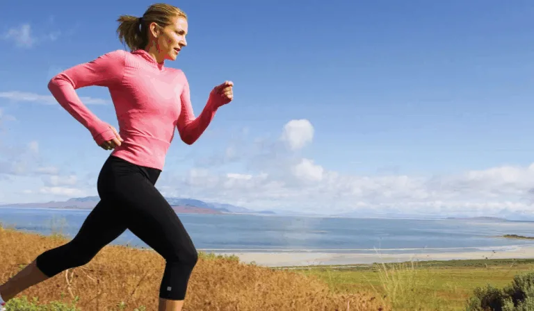 Woman enjoying a walk in nature with a water bottle and yoga mat