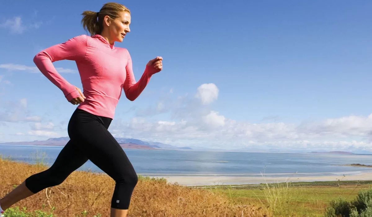 Woman enjoying a walk in nature with a water bottle and yoga mat
