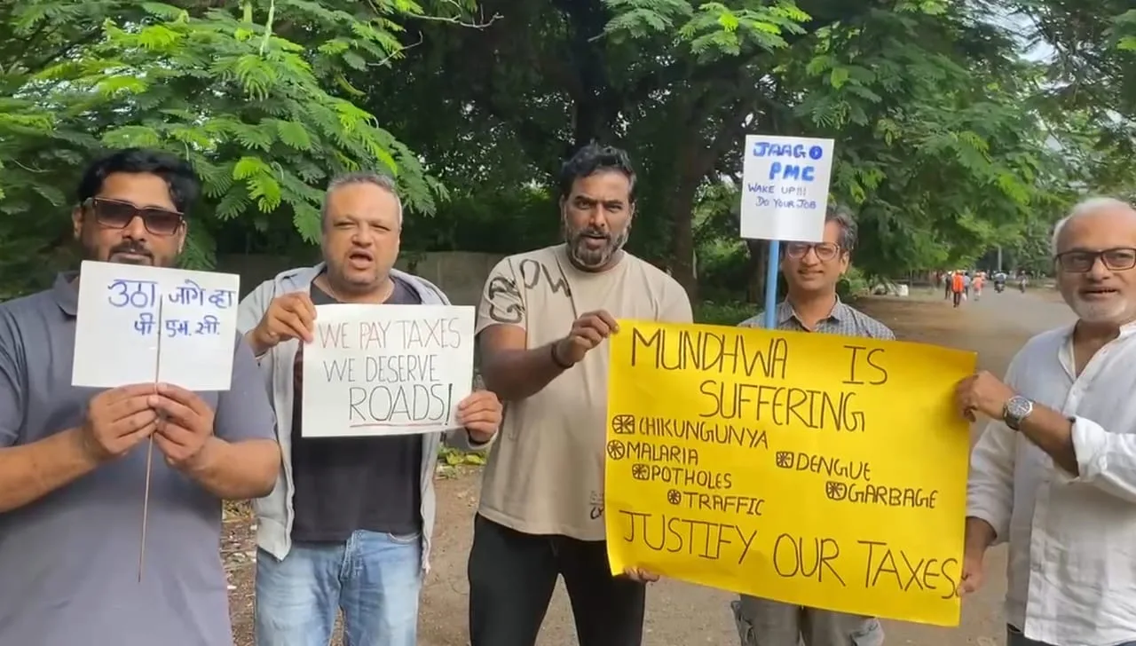 Residents holding protest signs outside Venkatesh Flora in Mundhwa, demanding PMC action