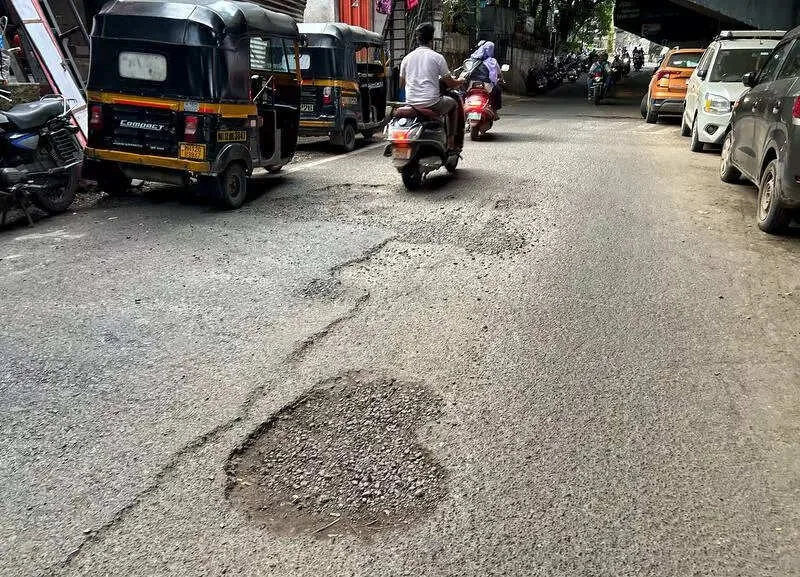 Severe pothole and damaged drain cover on a busy Pune street