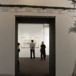 Visitors in an art gallery with artworks on the walls